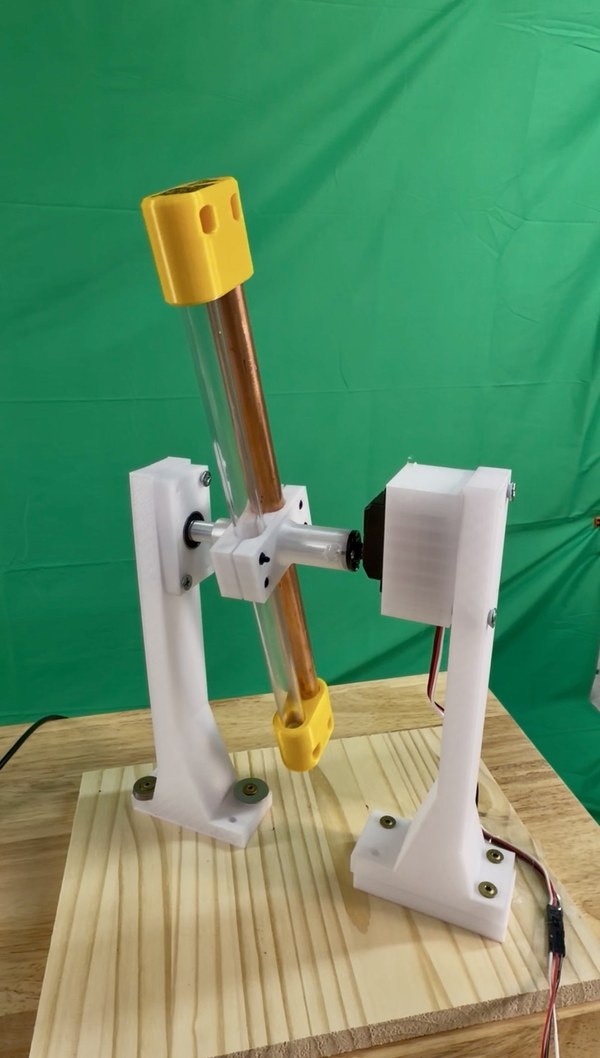 Dual-tube demonstrator mounted between two white towers on a motorized flip-test fixture.